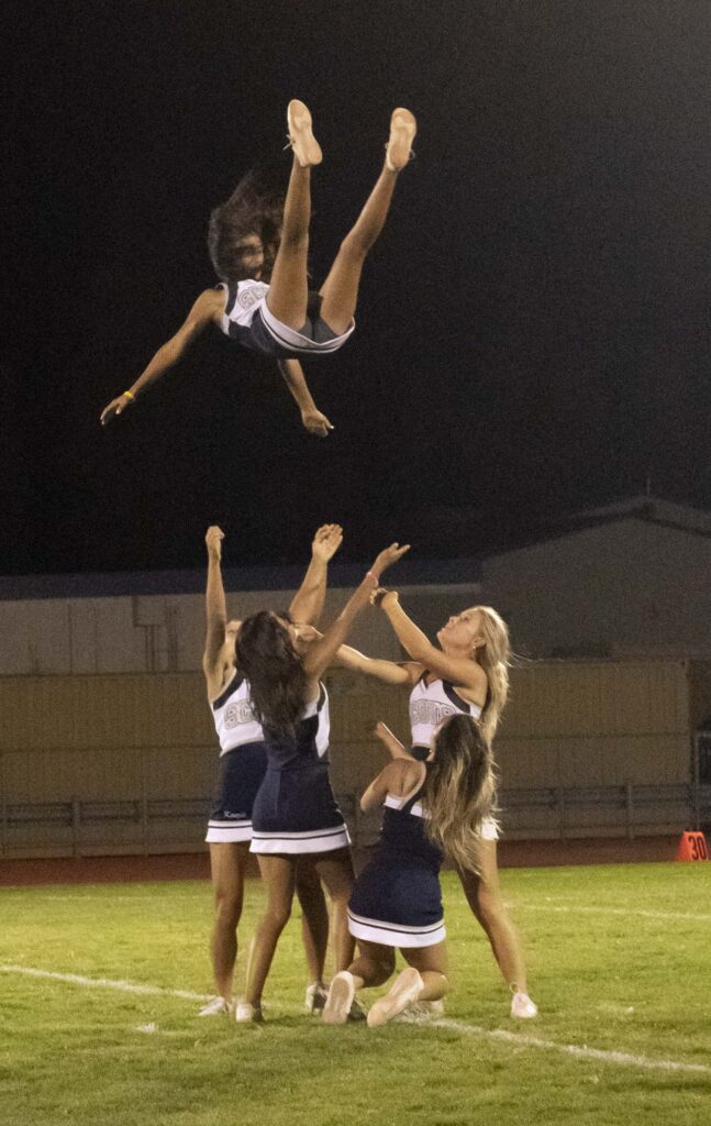 Cheerleaders doing a stunt on a football field.