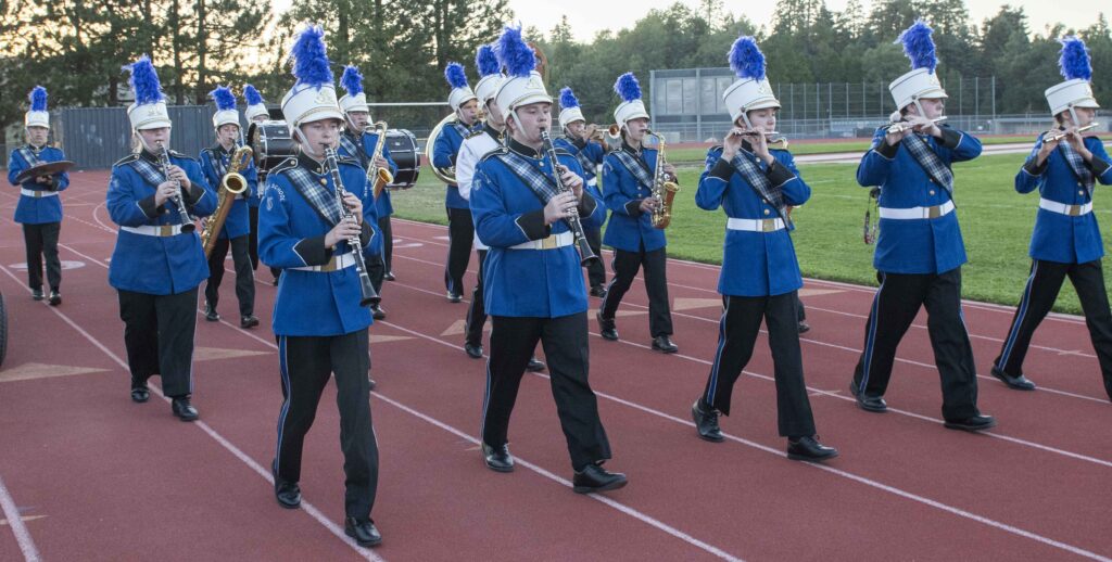 Marching band in blue uniforms on a track.