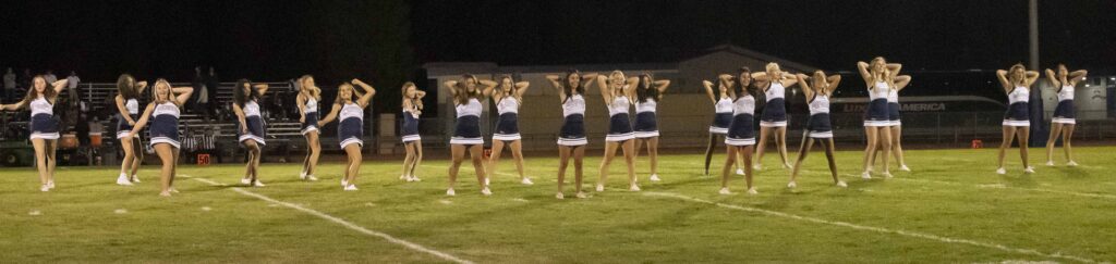 A group of cheerleaders standing on a field at night.