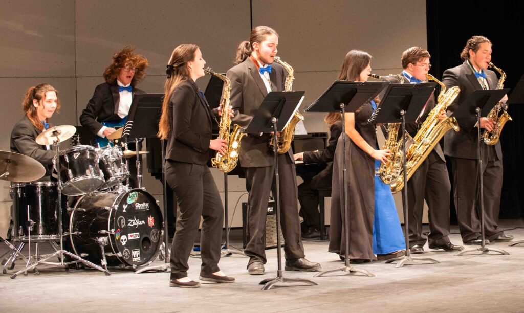 A group of people playing saxophones on stage.