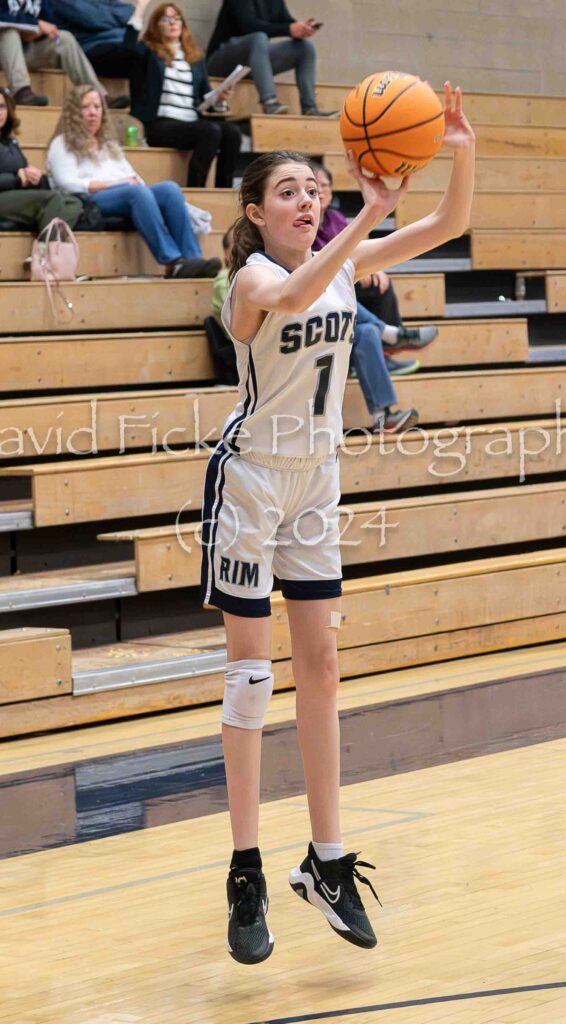 A girl in a basketball uniform taking a shot.