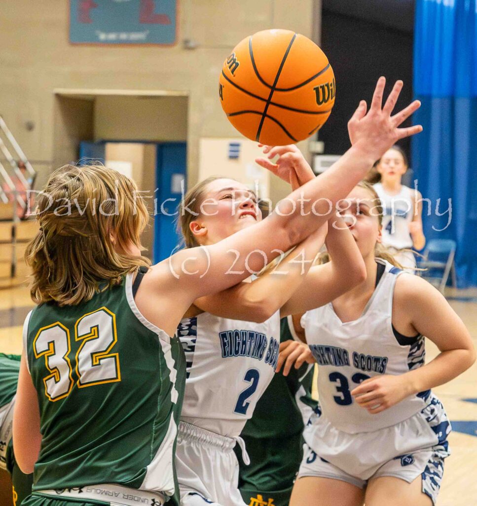 A girl is trying to block a basketball during a game.