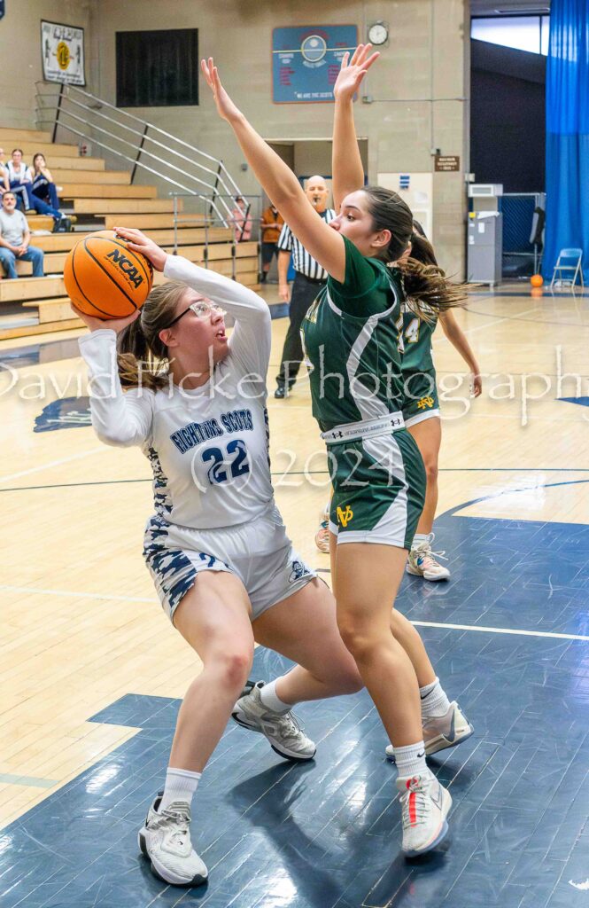 Two girls basketball players trying to block the ball.