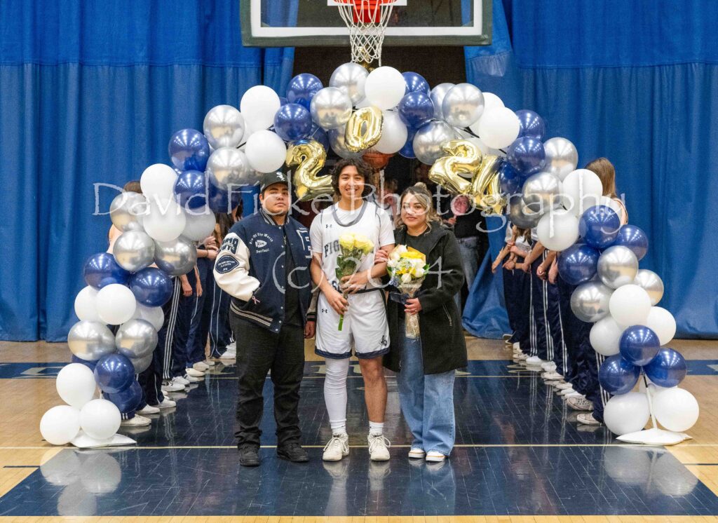 A group of people standing in front of a basketball court with balloons.