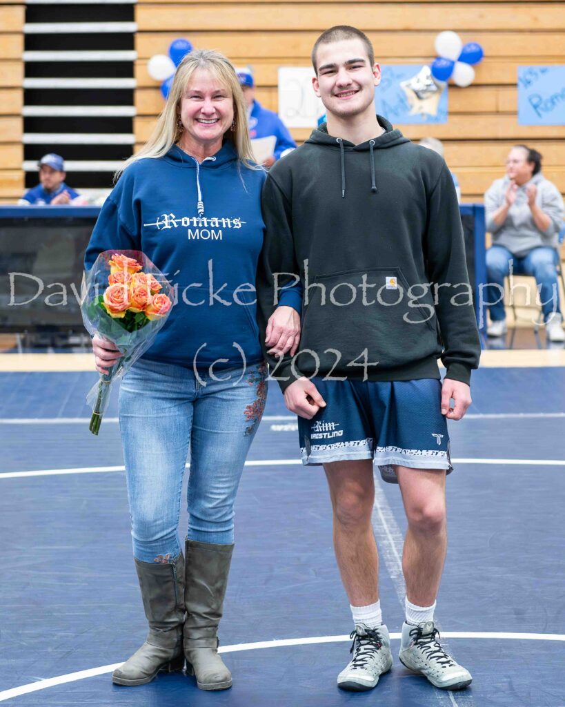 A man and woman standing next to each other on a wrestling mat.